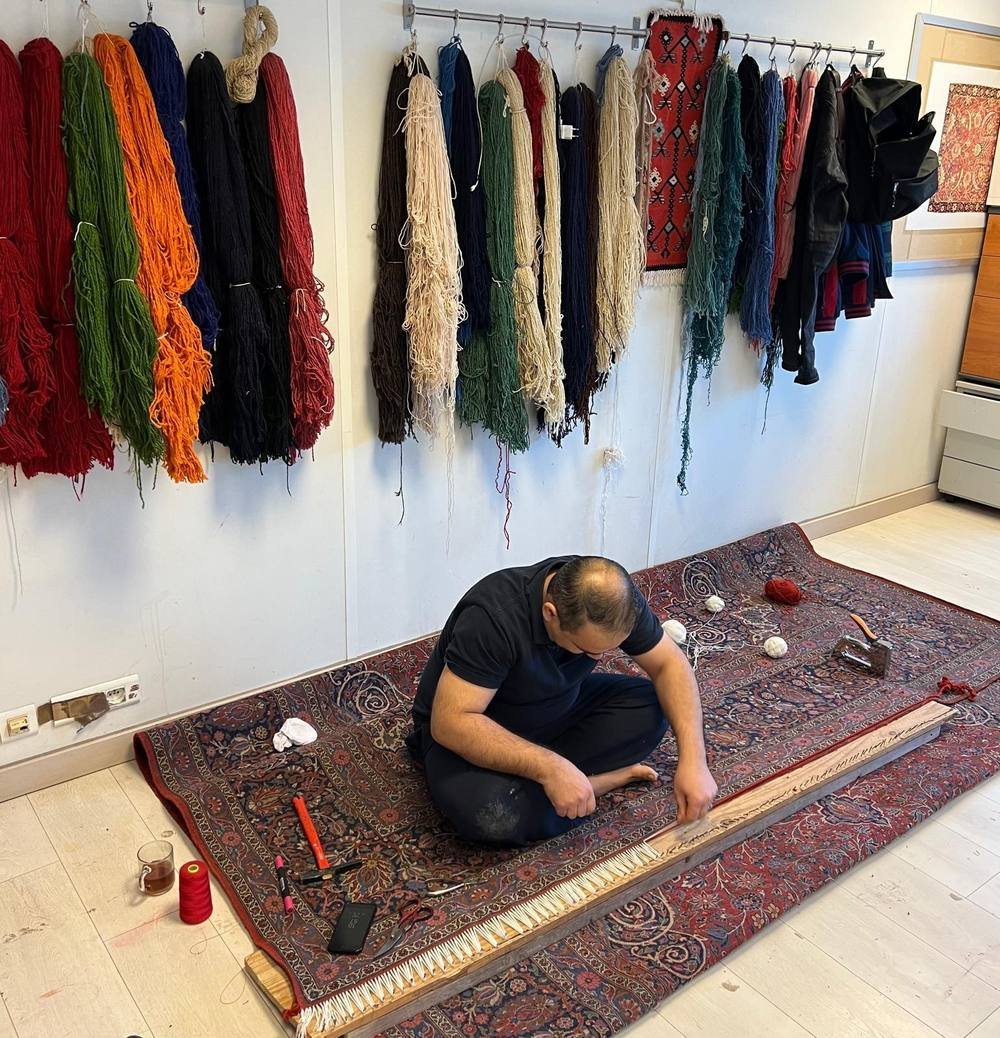 L’atelier : laines teintées au mur, pièces en cours au sol