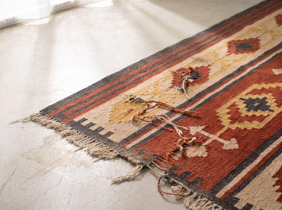 Un kilim ouvert par l’humidité d’une véranda — avant restauration