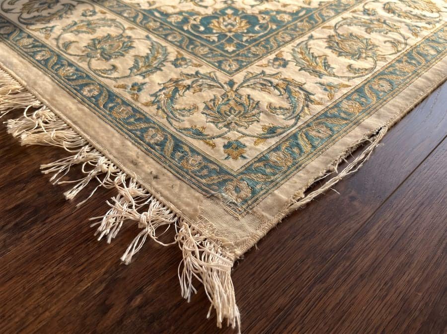 Un Qom en soie usé jusqu’à la chaîne dans un angle — avant restauration